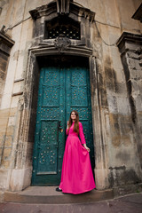 Fototapeta na wymiar Amazing girl in pink dress is standing near doors