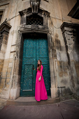 Fototapeta na wymiar Girl in pinkdress near old green doors