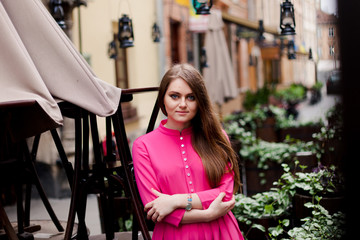 Serious young girl is standing near empty cafe