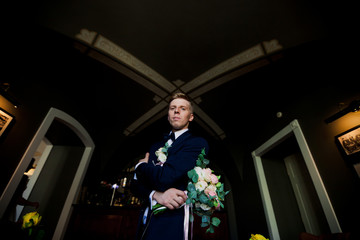 Fototapeta premium Handsome groom standing with amazing bouquet