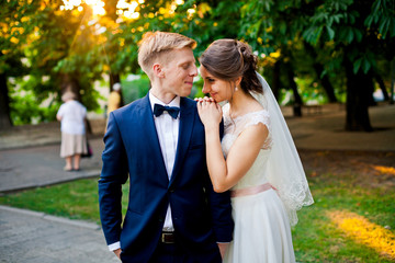 Obraz premium Attractive bride hugs her husband in the park