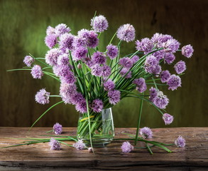 Bouquet of onion (chives) flowers in the vase on the wooden tabl