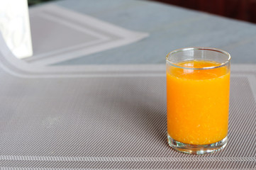 Small single glass of orange juice on napery