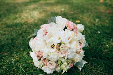 Wedding bridal bouquet of delicate pink and white flowers lying on green grass. wedding concept