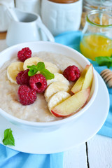 Oatmeal porridge with honey, banana, raspberries and peaches for