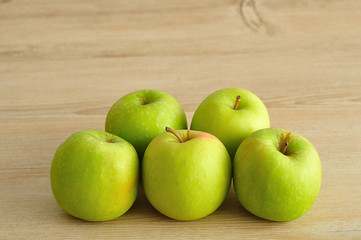 Green apples displayed on a wooden background.