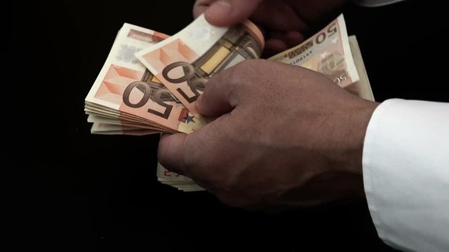 Businessman’s hands counting euro bills in darkness
