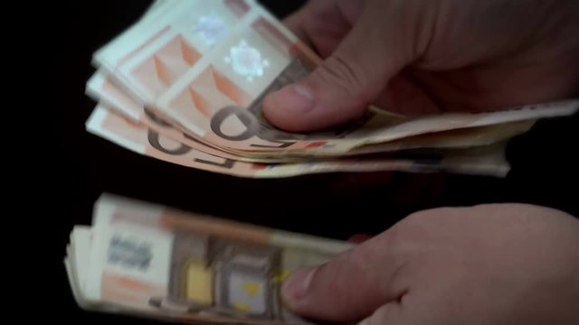 Businessman’s hands counting euro bills in darkness