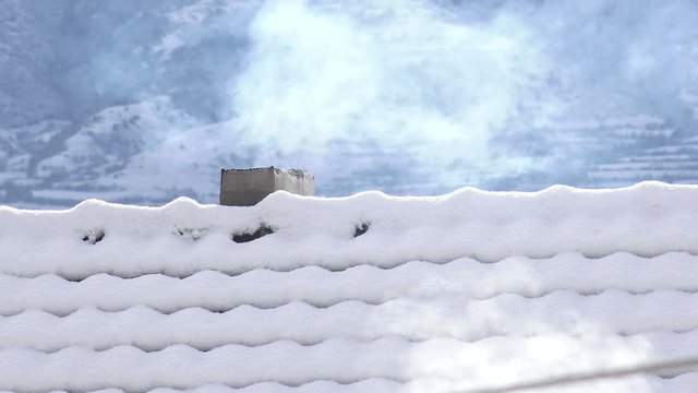 Snow capped roofs with smoke from the chimney, 