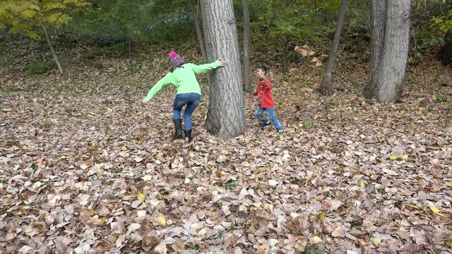 Kids running in forest throwing autumn leaves