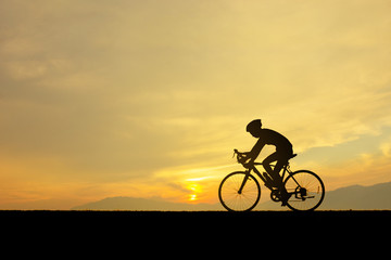 Fototapeta na wymiar Silhouette of man and him cycling on the lawn in sunset time.