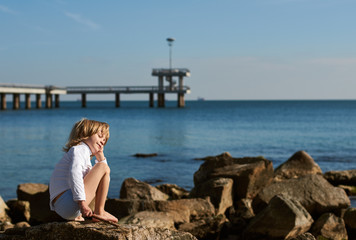 Fototapeta premium Young boy on sea beach rocks