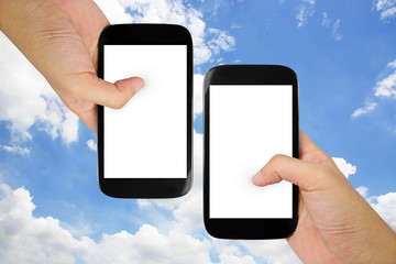 Hands holding smartphones with sky background