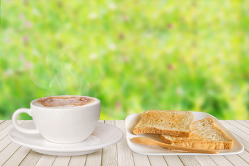 Cup of coffee and bread on white wooden table on bright background