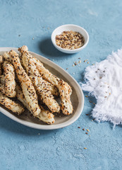 Puff pastry multi seeds bread sticks on a blue background.