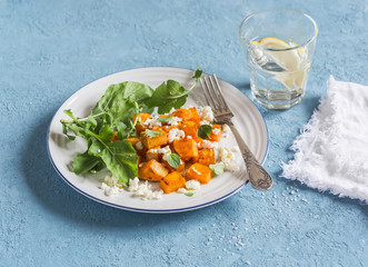Baked pumpkin and goat cheese salad on a blue background. Healthy food