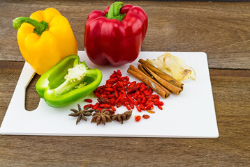 still - life concept sweet bell pepper and assorted spices for China Pharmaceutical Equipment (goji berries, cinnamon , anise , galangal , cardamom , pepper) in white block on wooden background