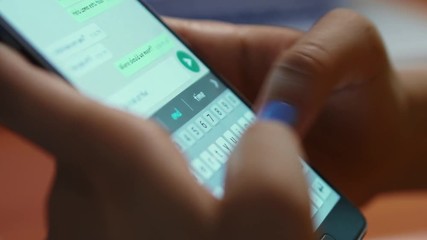 Young woman using smartphone while doing homework. Hispanic people and college education. Female student studying and texting with mobile telephone at home, typing text message on cell phone. Close-up - Powered by Adobe