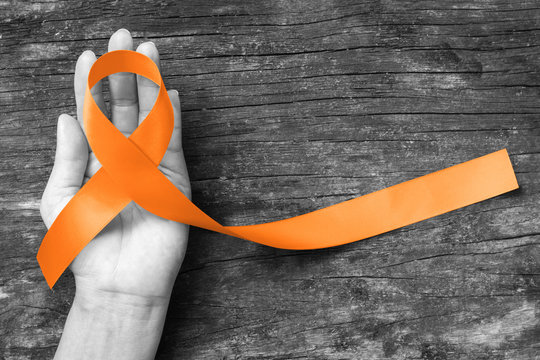 Orange ribbon for Leukemia, Kidney cancer, RDS multiple sclerosis awareness on helping hand symbolic bow color for supporting on patient with disease
