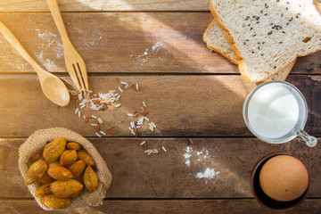 Low key of image of American breakfast on old wood table with sunshine ( boiled egg, bread, almond,milk) top view.