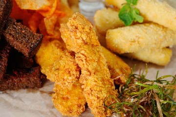 snack to beer on a large plate. Chips, crackers, cheese, onion rings, cheese sticks