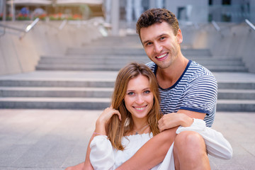 Youth and feelings. Dating. Attractive young loving couple sitting on stairs outdoors.