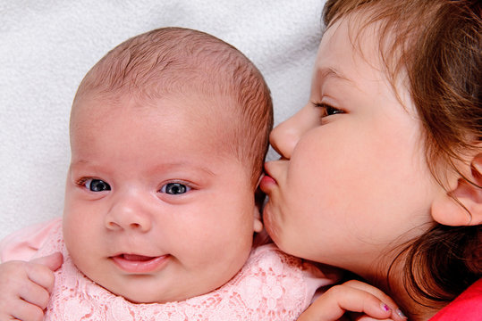 little girl kissing her baby- siste