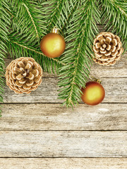 New Year or Christmas background: fir branches, goldish glass balls cones over old wooden backdrop, top view, copy space, tinted photo