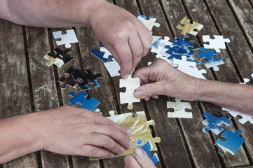 Seniorin setzt Puzzle zusammen / Seniorin sitzt an einem Tisch und setzt ein Puzzle zusammen mit einer Helferin.