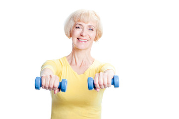 Health and sport. Cheerful aged woman exercising with dumbbells looking at camera. Isolated on white.