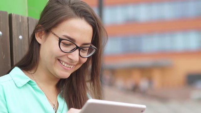 Beautiful student in glasses with a digital mini tablet