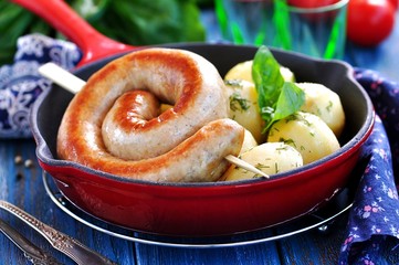 Home fried sausage with boiled potatoes and dill on a blue background.