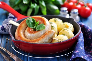 Home fried sausage with boiled potatoes and dill on a blue background.
