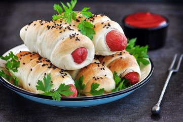 Sausage baked in pastry on a dark background.
