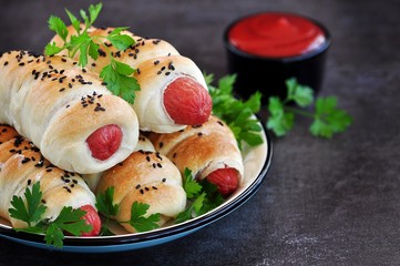 Sausage baked in pastry on a dark background.