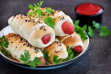 Sausage baked in pastry on a dark background.