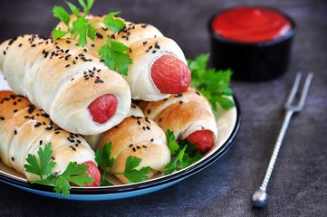 Sausage baked in pastry on a dark background.