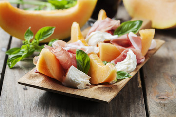 Antipasto with melon, mozzarella, ham and basil