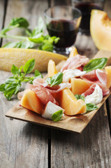 Antipasto with melon, mozzarella, ham and basil