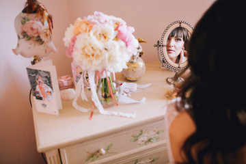 Beautiful young bride in a white dress. Last preparations for the wedding. The bride is waiting for the groom. Morning, the bride. Lokking at the mirror. Leg garter