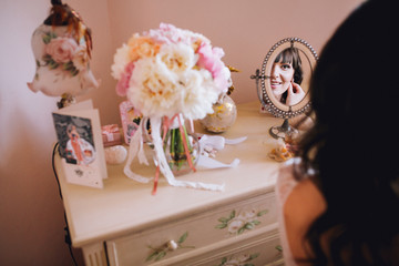 Beautiful young bride in a white dress. Last preparations for the wedding. The bride is waiting for the groom. Morning, the bride. Lokking at the mirror. Leg garter