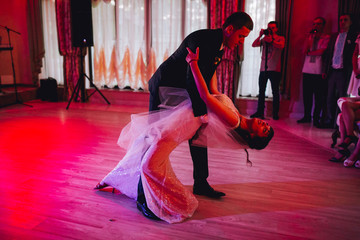 Fototapeta premium Happy bride and groom and their first dance, wedding in the elegant restaurant with a wonderful light and atmosphere