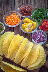 Mexican corn tortilla tacos with vegetables on wooden background