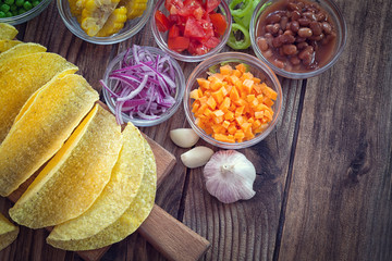 Mexican corn tortilla tacos with vegetables on wooden background