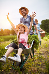 Girl having fun with farmer in vegetables garden
