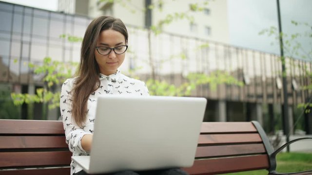 The girl looks at the laptop screen and typing on the keyboard