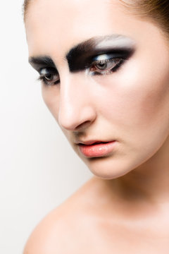 Young girl model with striking dark smokey eyes make up, looking down.