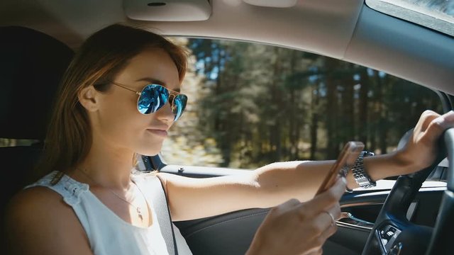 Young Woman in sunglasses Sending Messages while Driving