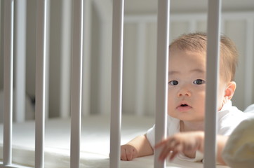 ベッドの柵ごしの赤ちゃん