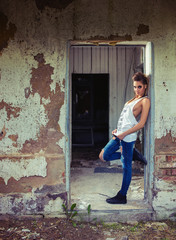 Punk style sexy attractive model girl posing in worn torn shirt and jeans at abandoned old factory in summer